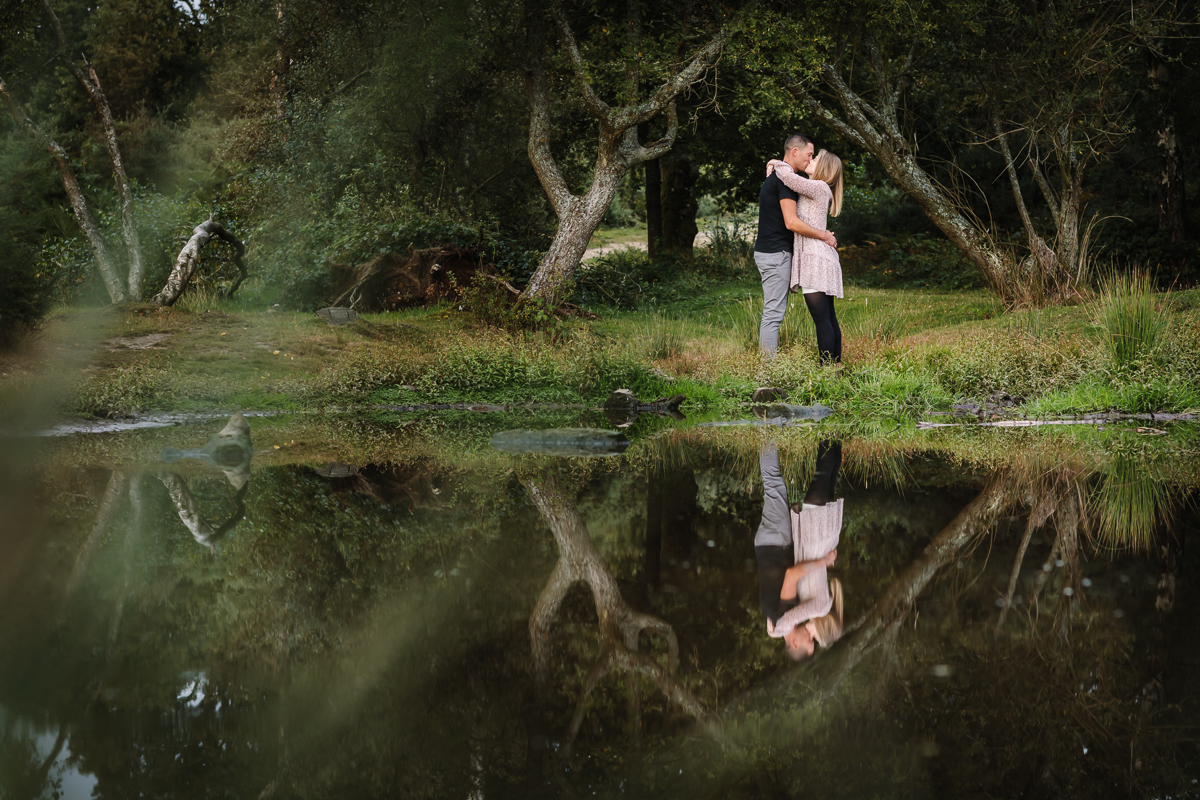 natural authentic image couple embrace reflection in water pond headily heath surrey hills unposed engagement session outdoor pre-wedding_shoot natural light documentary wedding photographer