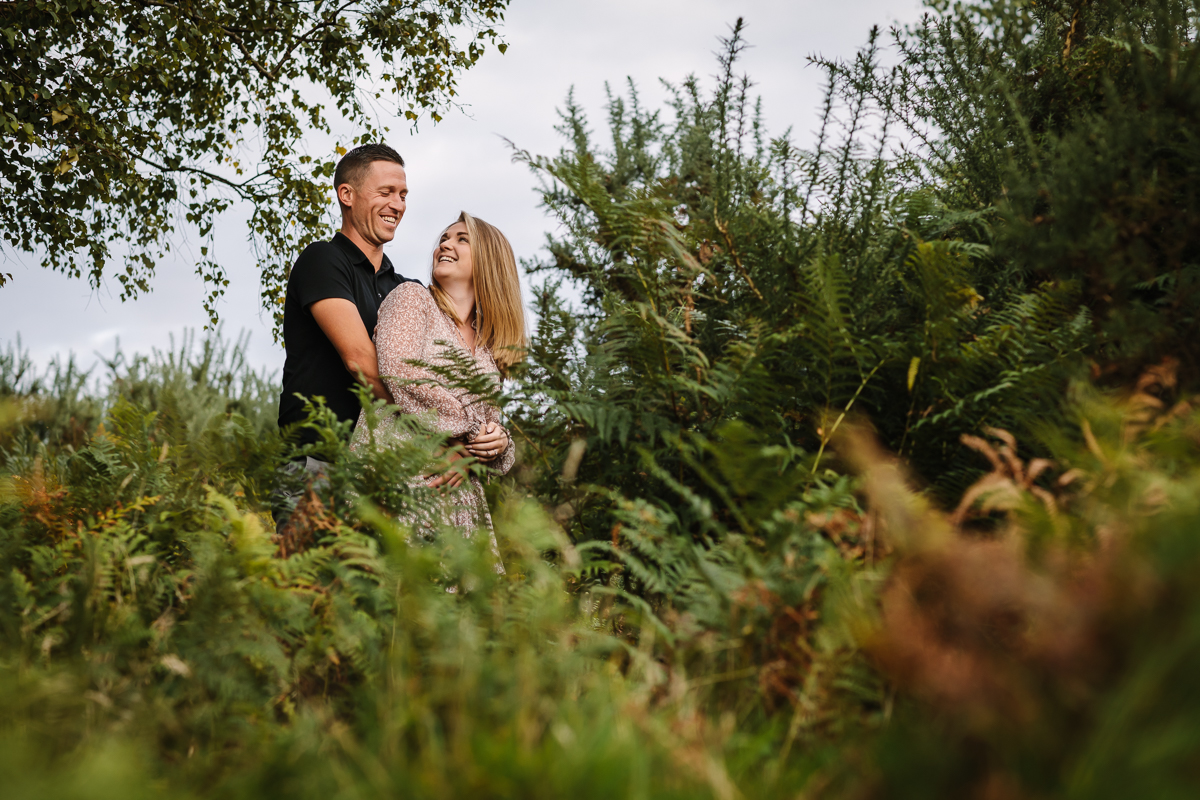 happy natural authentic image couple embrace in ferns headily heath surrey hills unposed engagement session outdoor pre-wedding_shoot natural light documentary wedding photographer