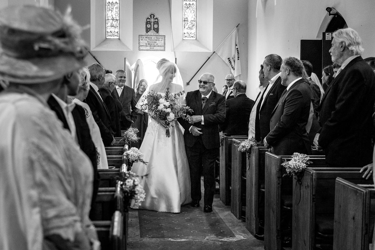bride and father_of_the_bride walk down the isle of brockham christ church wedding ceremony bride groom surrey natural and authentic wedding portraits by documentary wedding photographer surrey and sussex