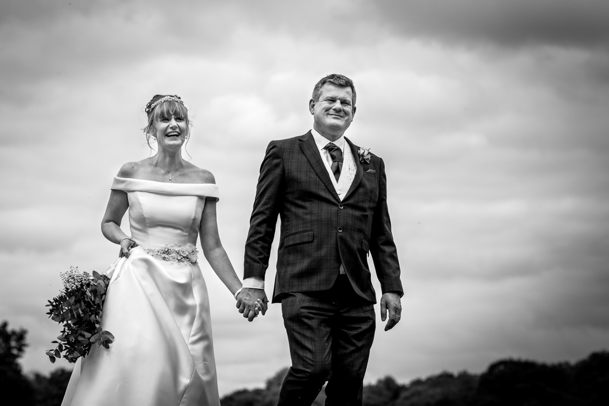 black_white image of bride groom wedding couple walking during portrait session at barn  wedding venue gildings farm newdigate surrey for natural authentic wedding portraits by documentary wedding photographer