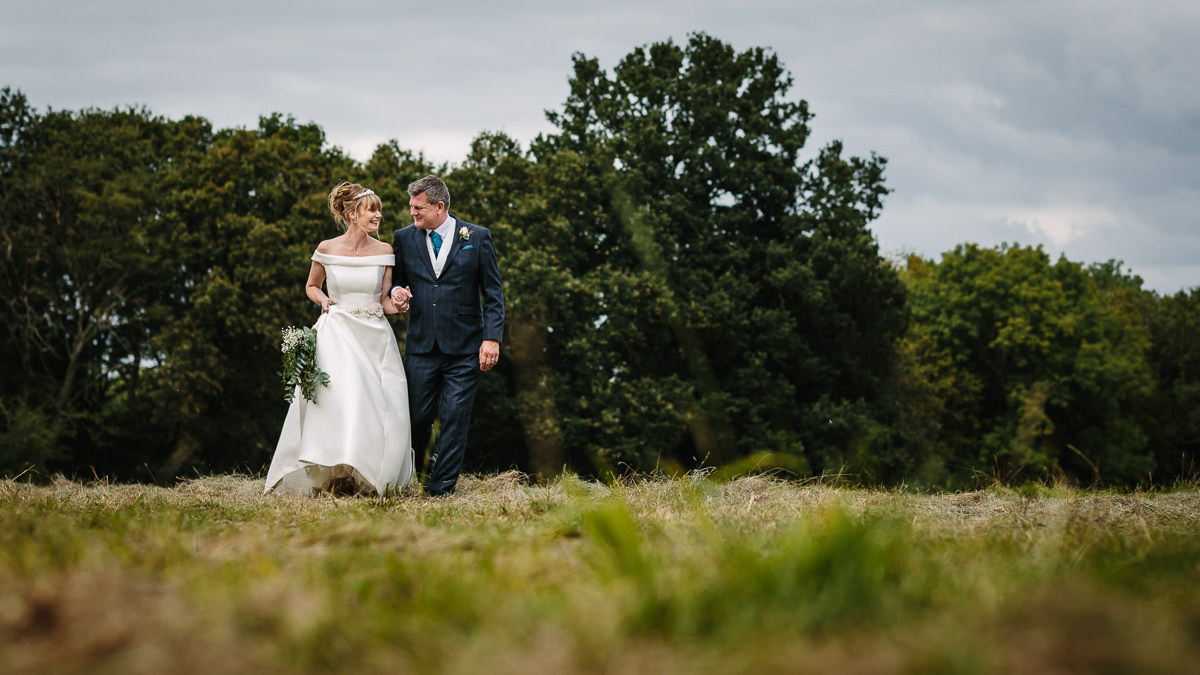 bride groom wedding couple walking during portrait session at barn  wedding venue gildings farm newdigate surrey for natural authentic wedding portraits by documentary wedding photographer