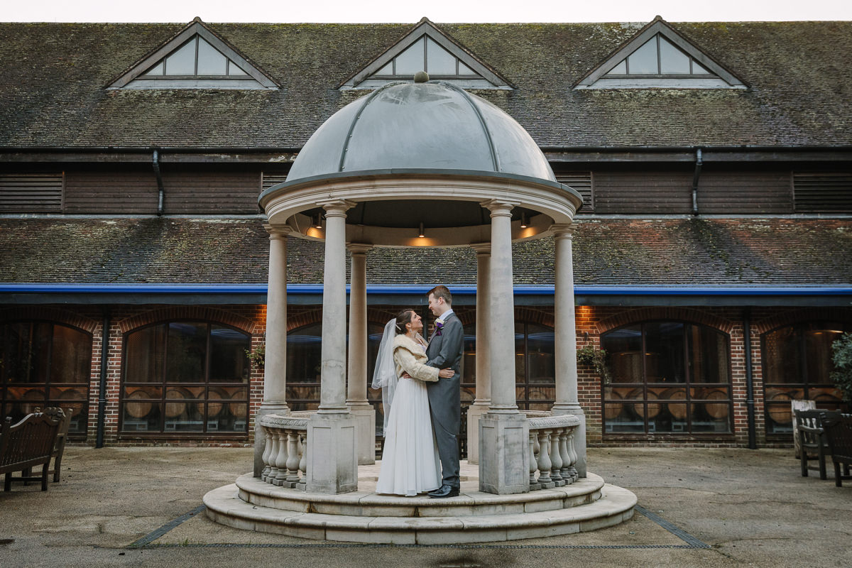 bride groom outdoor wedding portrait in courtyard pavilion at denbies vineyard dorking by documentary wedding photographer surrey for natural colourful and authentic wedding photography