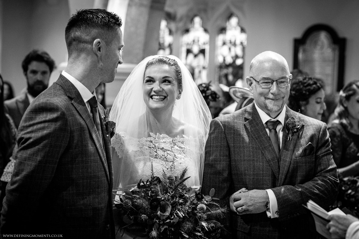 smiling bride at altar st_peter church newdigate religious wedding ceremony bride groom black_white photo natural and authentic wedding portraits by documentary wedding photographer surrey and sussex