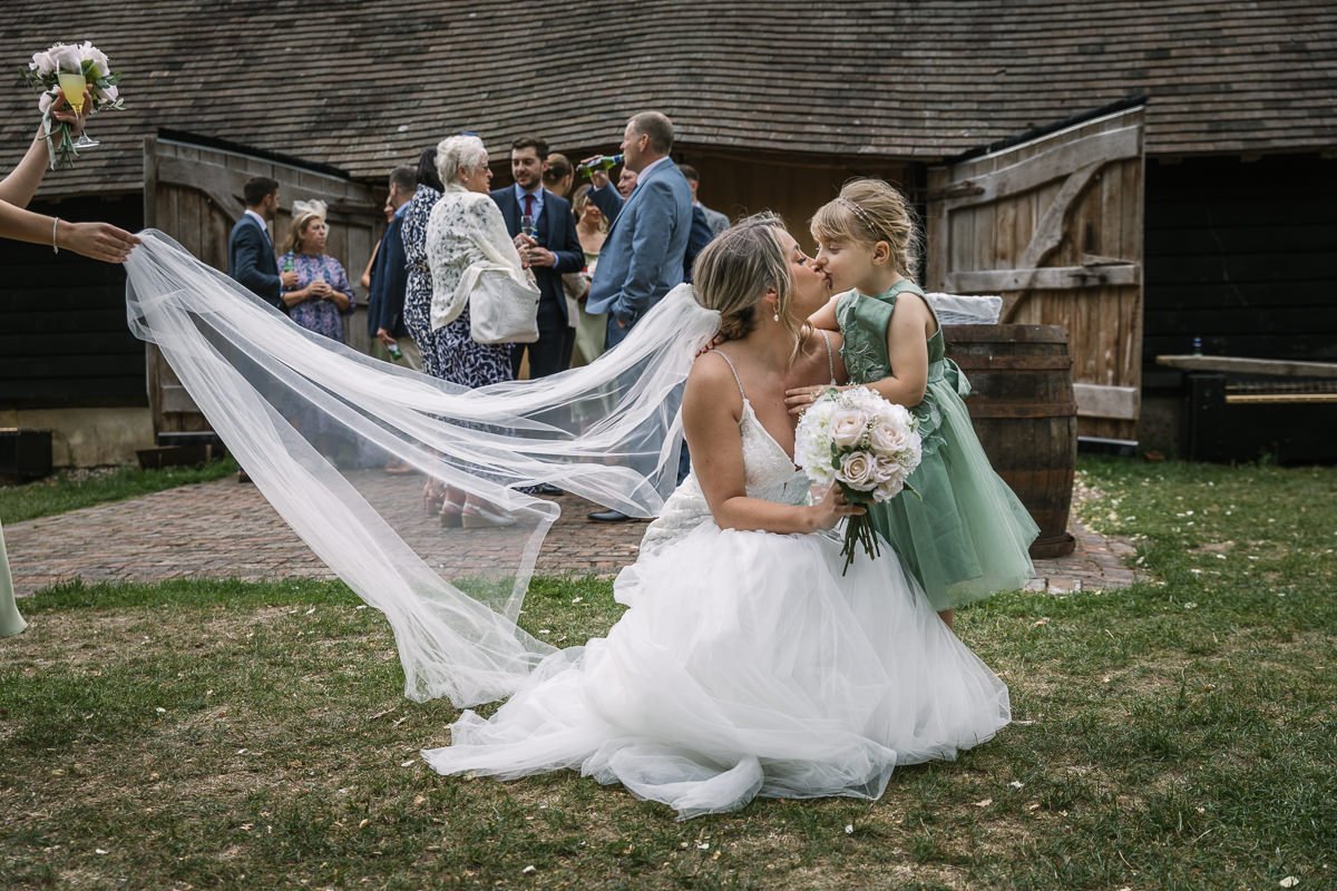 bride and flowergirl exchanging love at outdoor wedding reception gildings barns surrey unposed natural candid documentary photography sussex