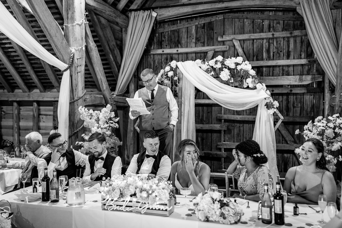 black_and_white image of wedding breakfast speeches at gildings barns surrey unposed natural candid documentary photography sussex