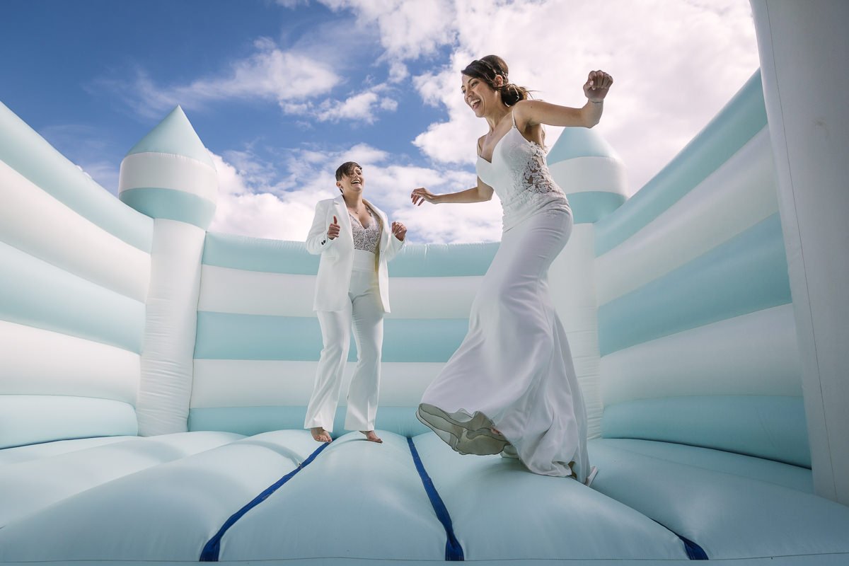 brides jumping and having fun on the bouncy castle at their same_sex gay wedding at gildings_barns with natural unposed candid photography by LGBTQ friendly wedding photographer surrey sussex