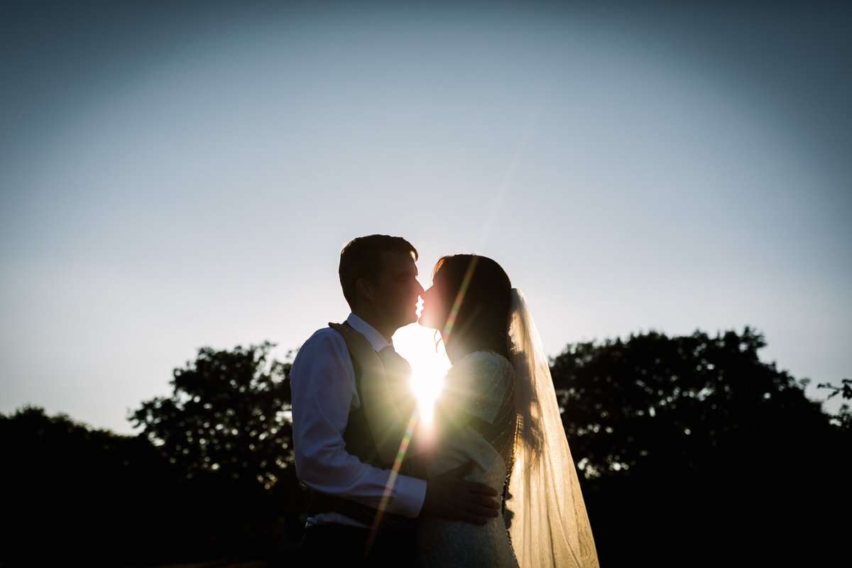 golden_hour silhouette bride groom outdoor wedding portrait at barn wedding venue kent the_plough_at_leigh by documentary wedding photographer surrey sussex for natural colourful and authentic LGBTQ_friendly wedding photography