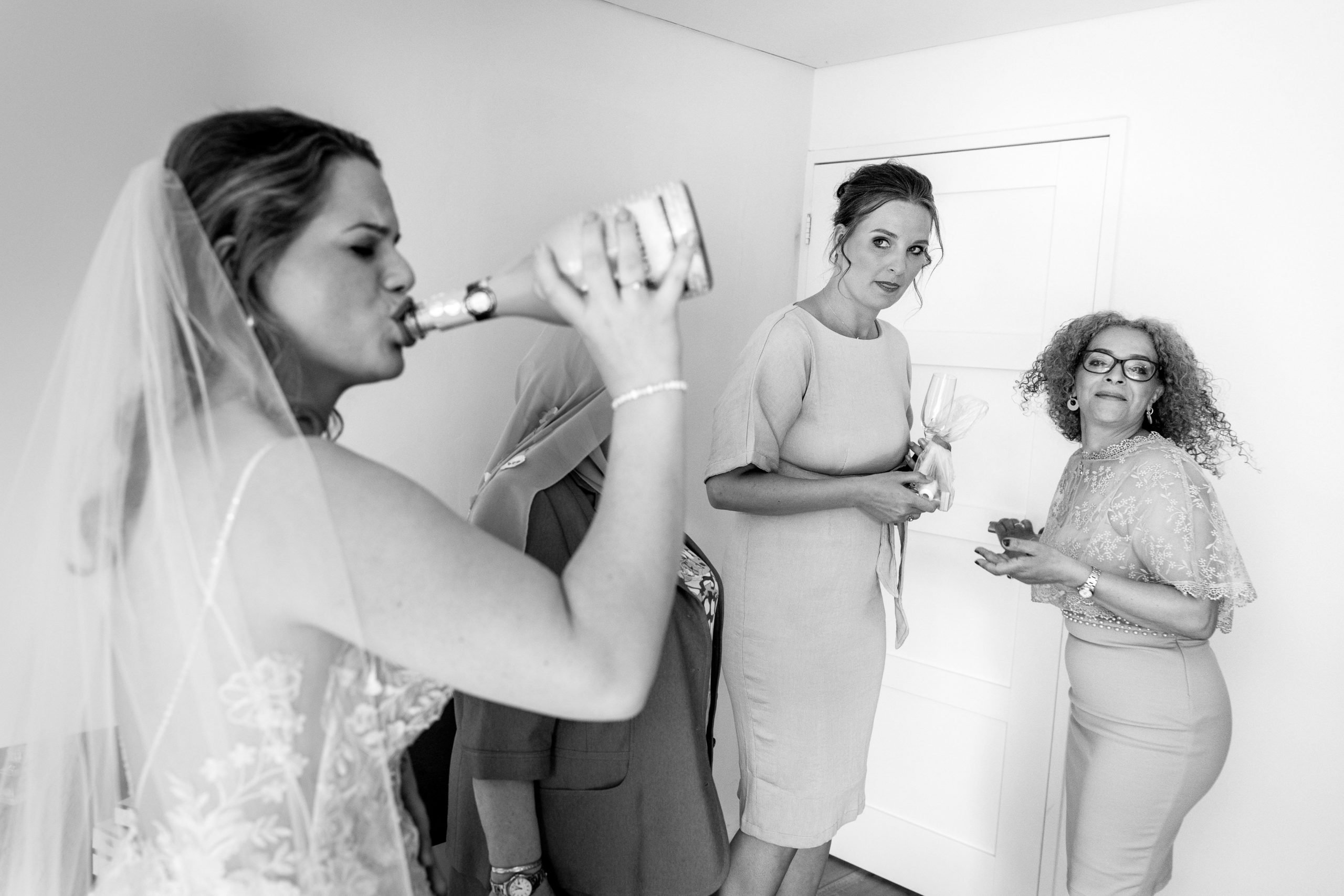 bride drinking bubbly straight from the bottle before start of wedding day natural unposed candid wedding photography by LGBTQ_friendly documentary wedding photographer surrey sussex