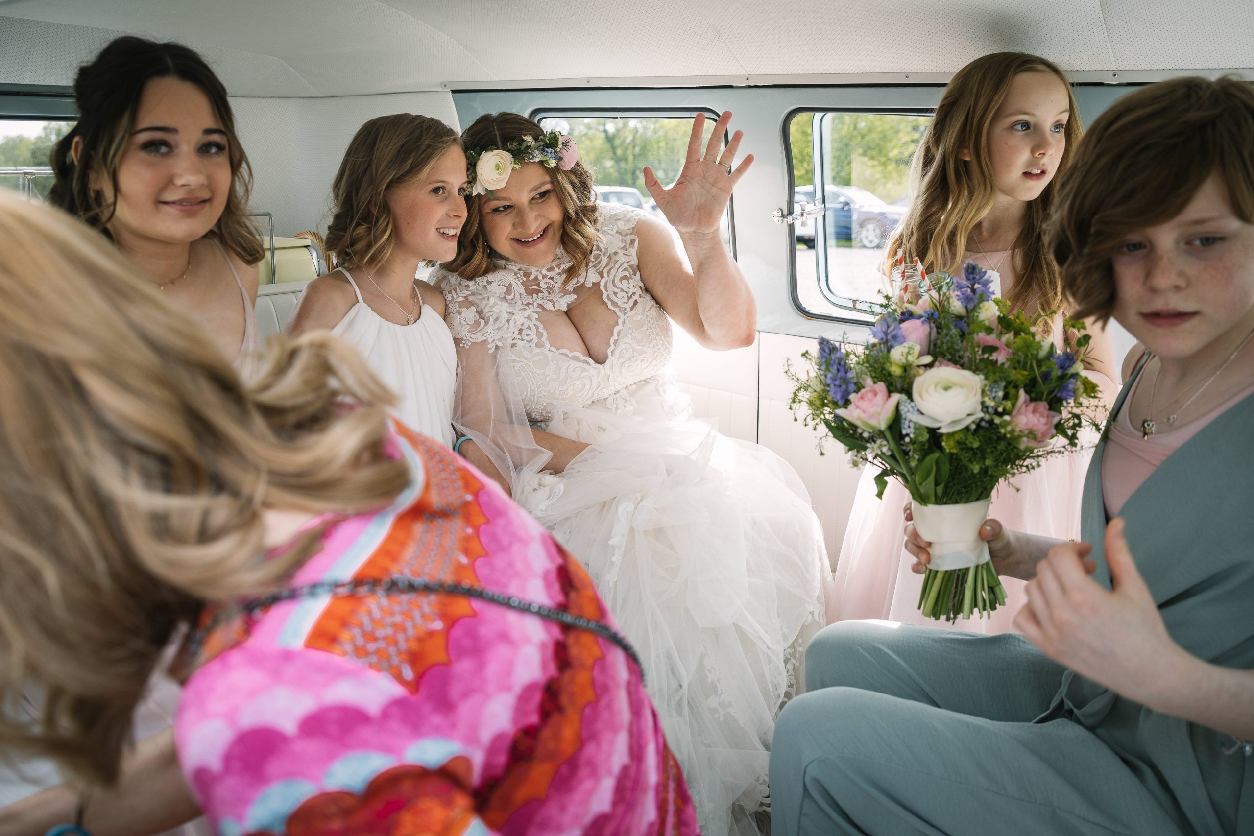 bride and bridal party arriving at venue gildings_barns on wedding day in volkswagen campervan and waving at camera natural unposed candid wedding photography by LGBTQ_friendly documentary wedding photographer surrey sussex
