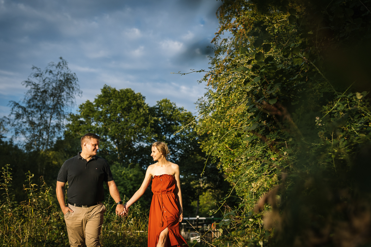 couple walking and looking at each other in the warm sunlight of the golden hour candid engagement_shoot relaxed Pre_wedding_shoot sussex surrey by documentary wedding photographer