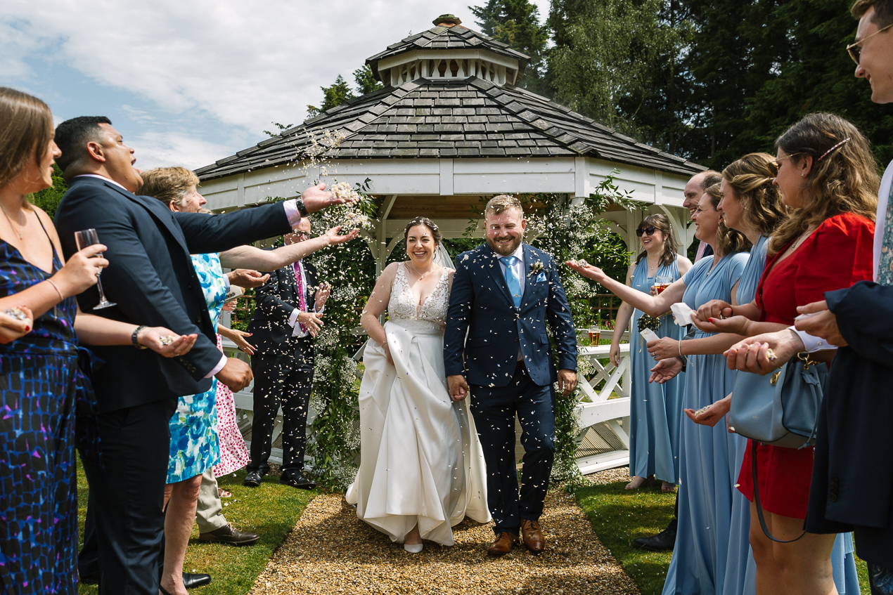 bride and groom confetti throw after wedding ceremony outside at Hartsfield_Manor_wedding Surrey by documentary wedding photographer surrey for candid natural unposed authentic documentary photography
