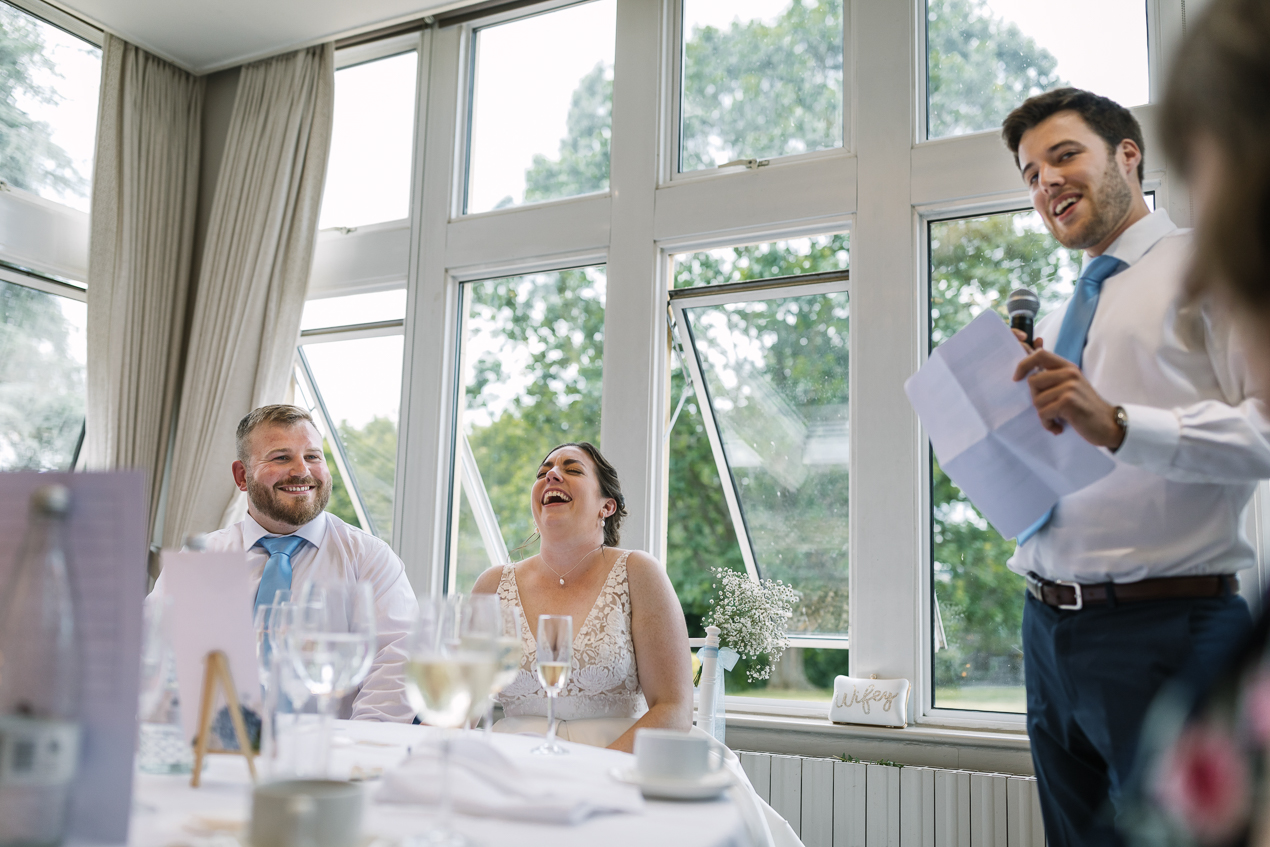 bride and groom laughter during wedding breakfast speeches during wedding at Hartsfield_Manor_wedding Surrey by documentary wedding photographer surrey for candid natural unposed authentic documentary photography