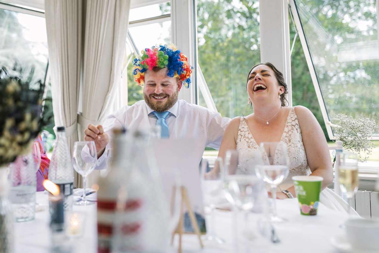 bride and groom laughter during wedding breakfast speeches during wedding at Hartsfield_Manor_wedding Surrey by documentary wedding photographer surrey for candid natural unposed authentic documentary photography