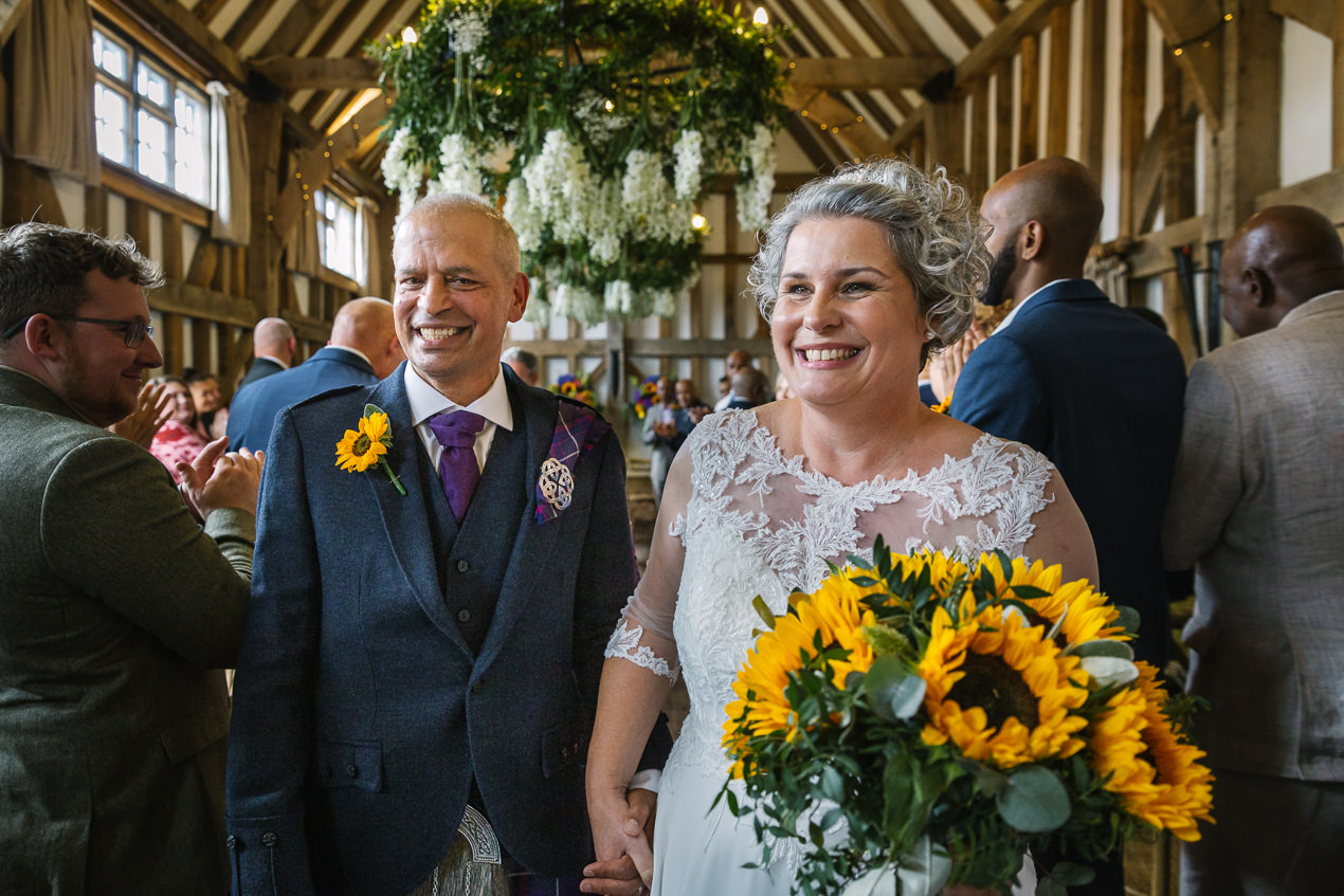 just married couple leaves the barn after the wedding ceremony at gate_street_barn wedding storytelling wedding photography by documentary wedding photographer surrey sussex