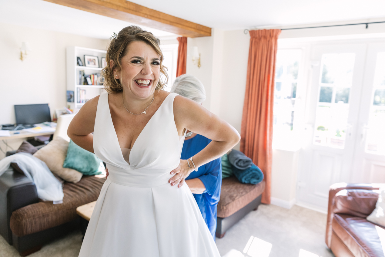 colour image of bride getting ready in wedding dress candid gildings_barns wedding photography by documentary wedding photographer surrey sussex