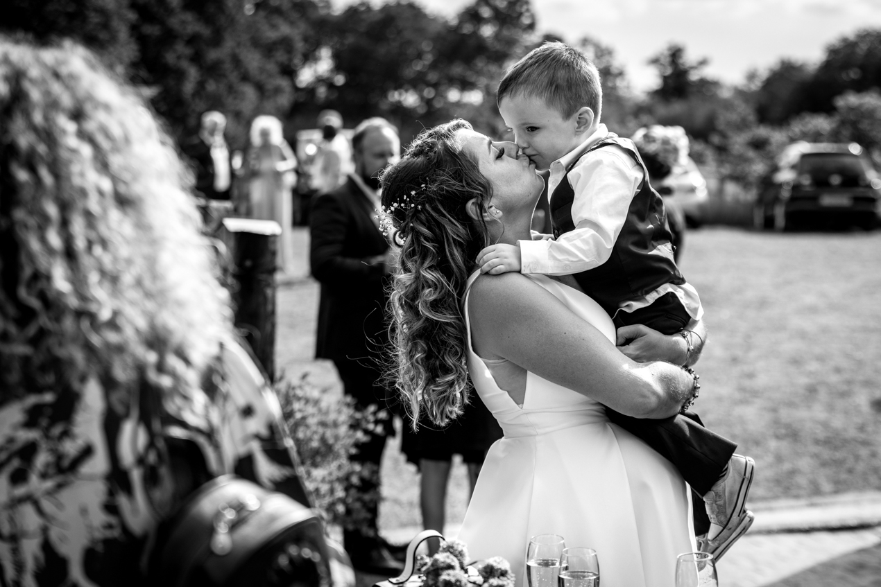black_white image loving embrace between bride and her son candid gildings_barns wedding photography by documentary wedding photographer surrey sussex